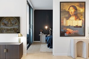 A modern room with a large painting, a desk, and a bed. - Art-Filled Loft: 50m Beach, King, Parking (Terrigal)