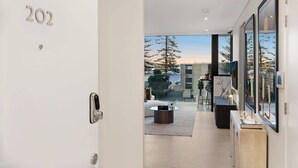 En modern inredning med en dörr märkt med nummer 202, utsikt över omgivningen och ett minimalistiskt vardagsrum med ett soffbord och ett sidobord.