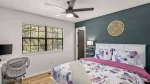 A bedroom with a bed, a desk, a chair, a ceiling fan, a window, and a decorative wall piece. - Back-40 Retreat with Hot Tub & Bike Garage (Bella Vista)