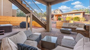 Une terrasse extérieure couverte, aménagée avec un canapé, une table basse et un jacuzzi.