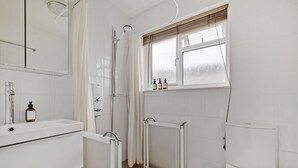 Un baño con ducha, inodoro, lavamanos y ventana con vistas.