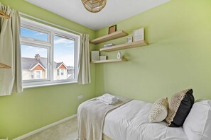A bedroom with a bed, a window, and a view of houses outside. - Modern, Homely 3 bed in Central Plymouth w/ Parking (Plymouth)
