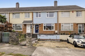 A row of terraced houses with a car parked in the driveway.