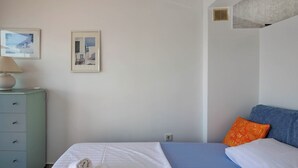 Un dormitorio con una cama, un aparador y dos cuadros en la pared.