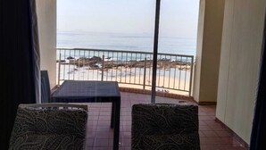 A balcony with a view of the sea, featuring a table and two patterned chairs. - 316 Cozumel (eMdloti)