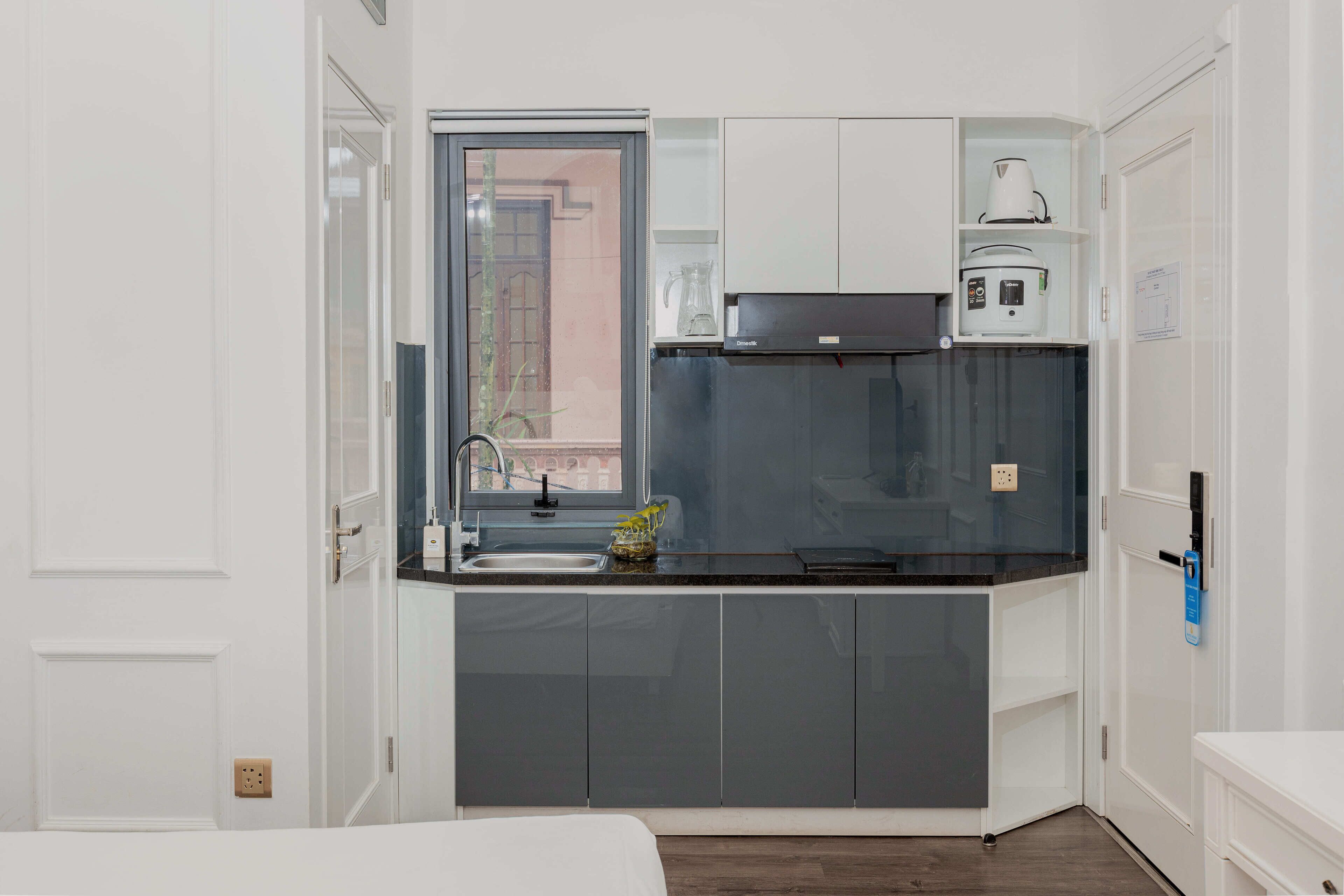 A compact kitchen with a sink, a stove, and a coffee maker.