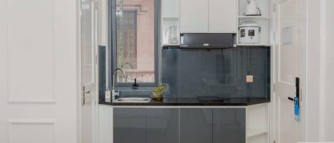 A compact kitchen with a sink, a stove, and a coffee maker.