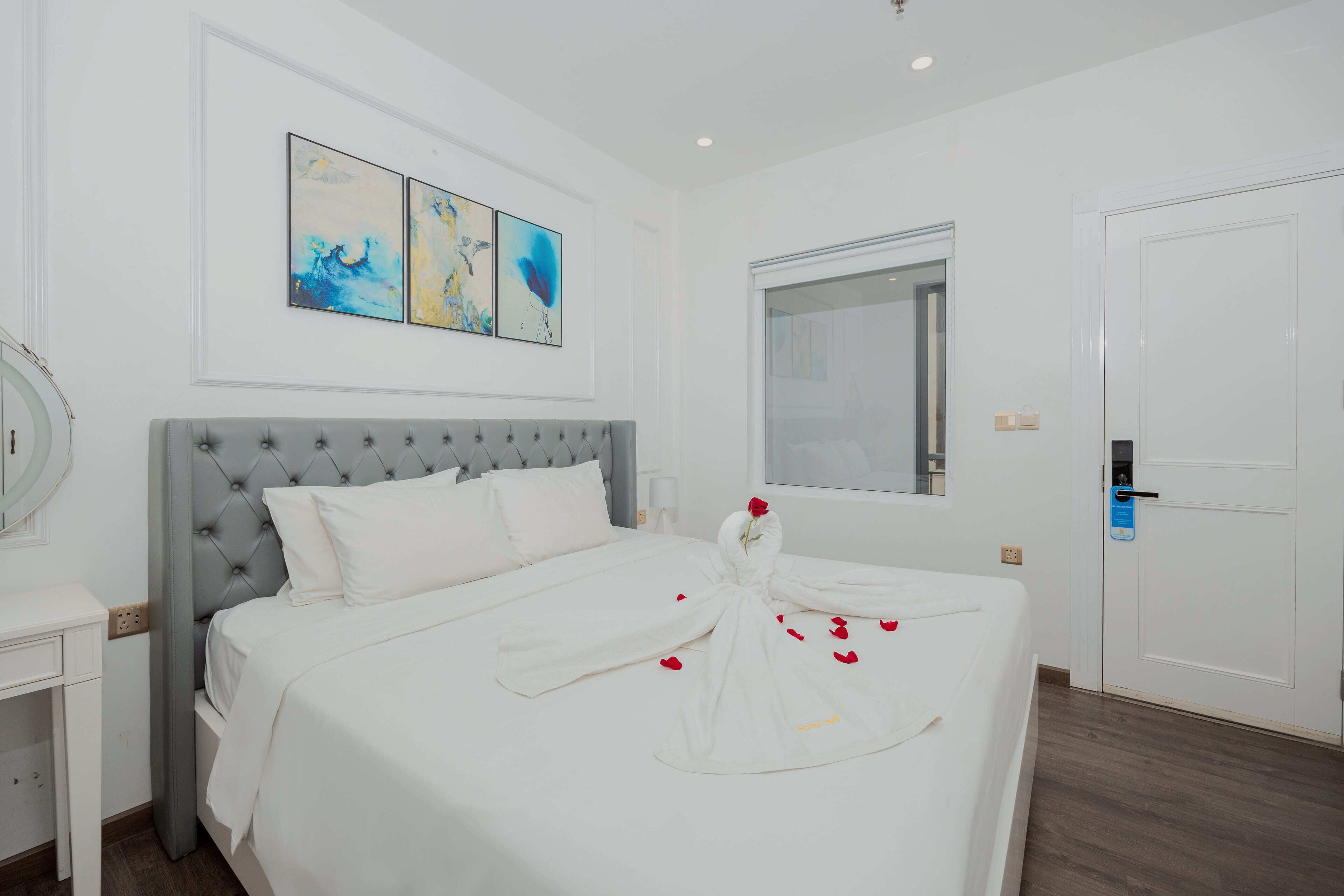 Ein Hotelzimmer mit Bett, Nachttisch, Spiegel, Fenster und Wandbild.