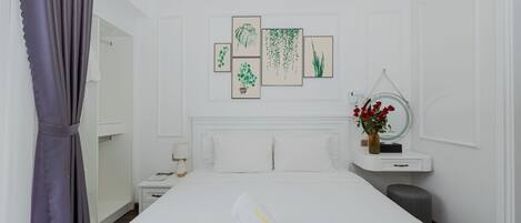 A hotel room with a bed, a nightstand, a mirror, a small table, and a window with curtains.