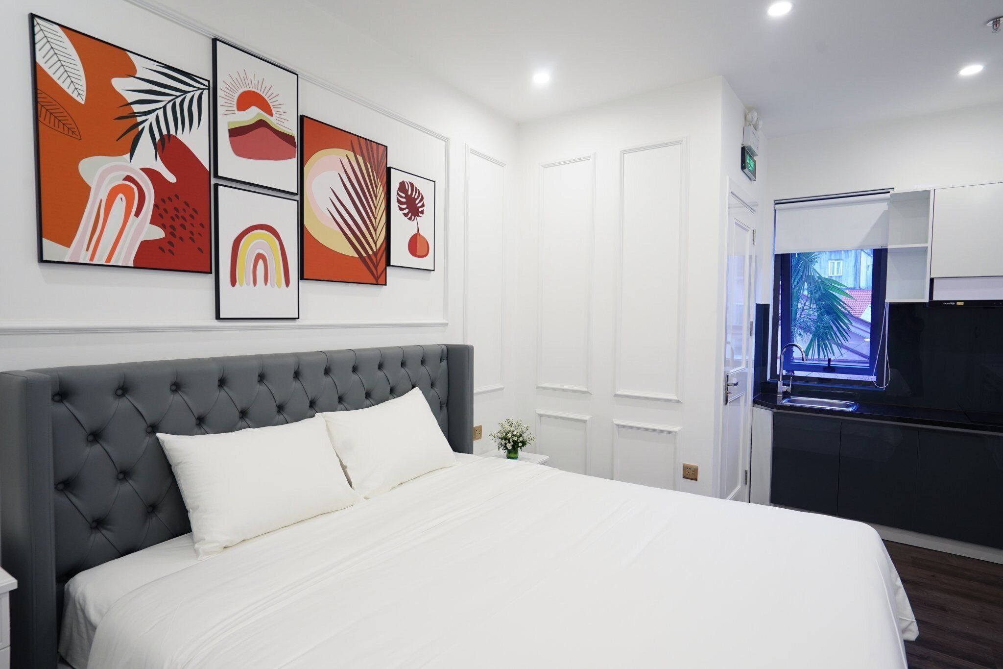 A hotel room with a large bed, a TV, and artwork on the wall.