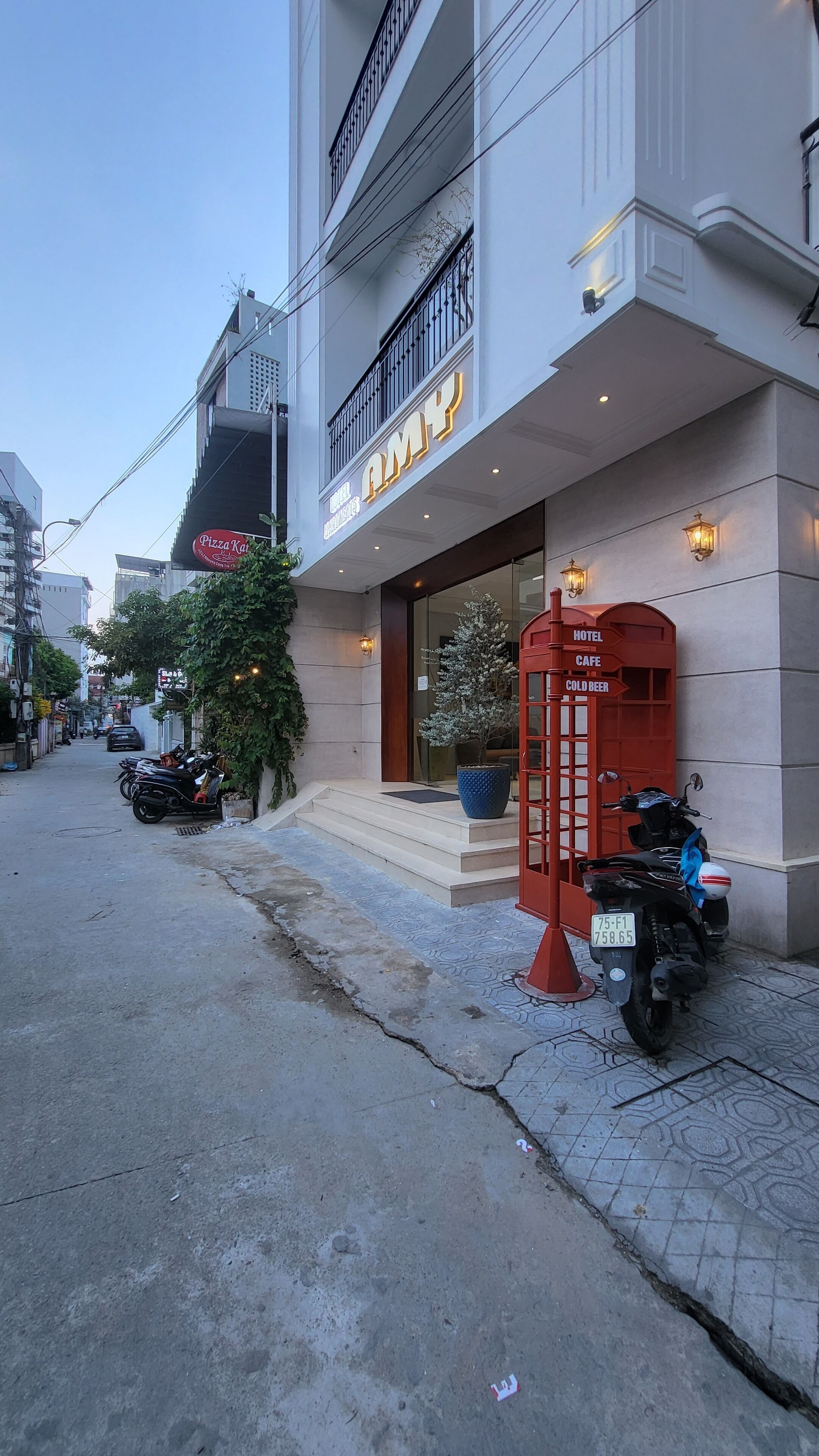 Un hotel con fachada moderna, una entrada visible y un teléfono rojo.