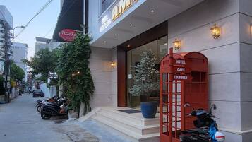 Un hotel con fachada moderna, una entrada visible y un teléfono rojo.