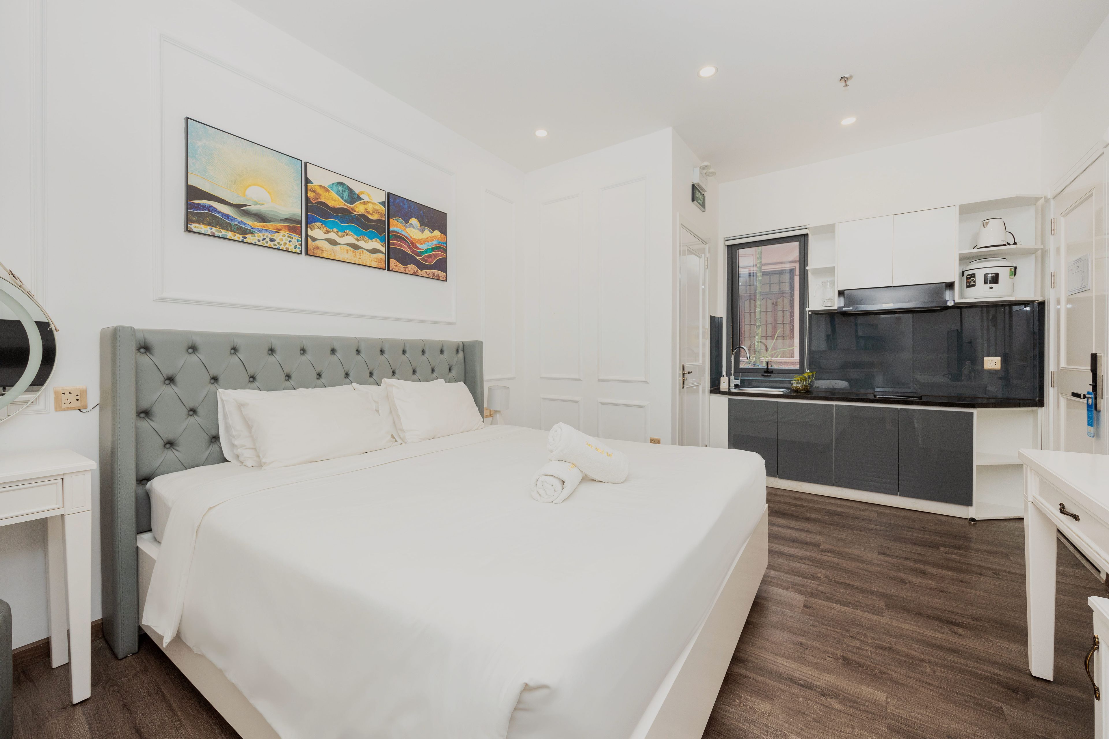 Ein Hotelzimmer mit Bett, Schreibtisch, Küchenzeile und Bildern an der Wand.