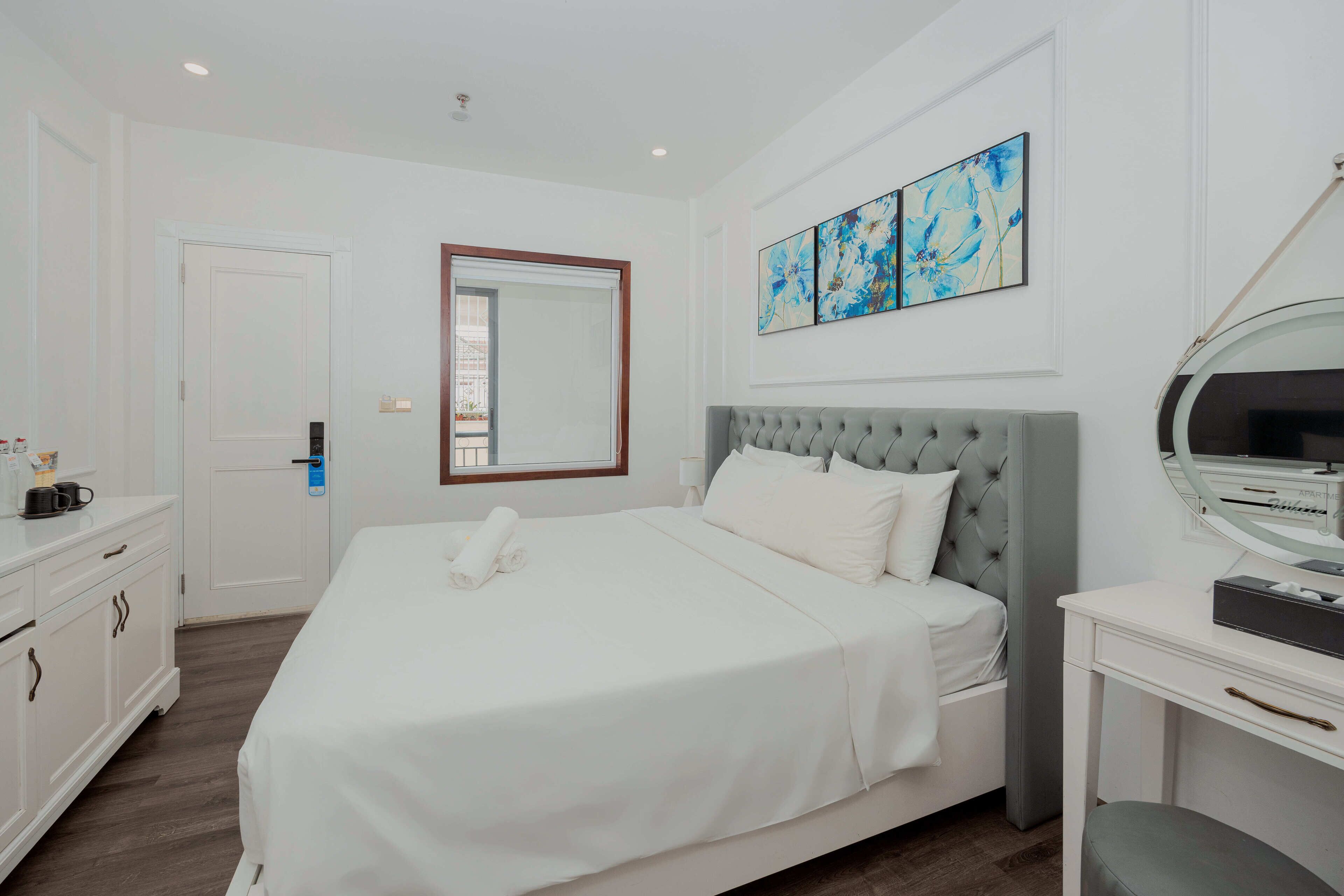 Una camera d'albergo con un letto, un comodino, uno specchio e una porta.