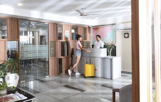 A reception area with a wooden reception desk, a clock on the wall, and a ceiling fan.