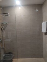 Un bagno moderno con cabina doccia in vetro, soffione doccia manuale e porta asciugamani.