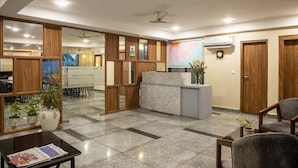 A modern reception area with a marble counter, wooden partitions, and a large flower vase. - Perch Arbor Cyber City (Gurugram)