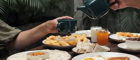 Desayuno con diferentes platillos, incluyendo tostadas, huevos y una taza de té siendo servido.
