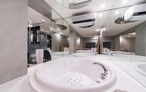 A modern bathroom with a large oval bathtub, a separate sink, and a mirror reflecting the room.