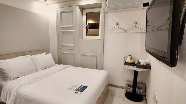 A hotel room with a bed, a television, a small table with a kettle, and a wardrobe. - Simple Stay Jongro (Seoul)