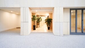 Een moderne entree met een strak betegelde vloer en grote potplanten.