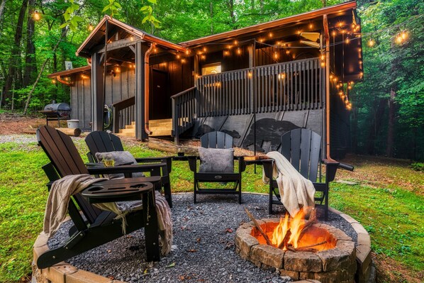 Un chalet rustique doté d’un foyer extérieur et de sièges pour profiter de l’extérieur.