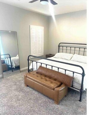 Cozy retreat with a bed, leather bench, and mirror.