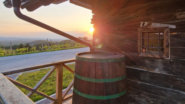 Ein hölzernes Fass auf einer Terrasse mit Blick auf den Sonnenuntergang.