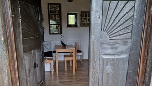 Eine rustikale Holztür führt in einen Raum mit Holzboden, einer Bank und einem Tisch mit einer Schüssel darauf.