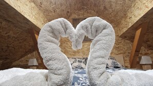 Ein Schlafzimmer mit Holzboden, einem Bett mit floralem Überwurf und zwei aus weißem Stoff gefertigten Schwänen auf dem Bett.