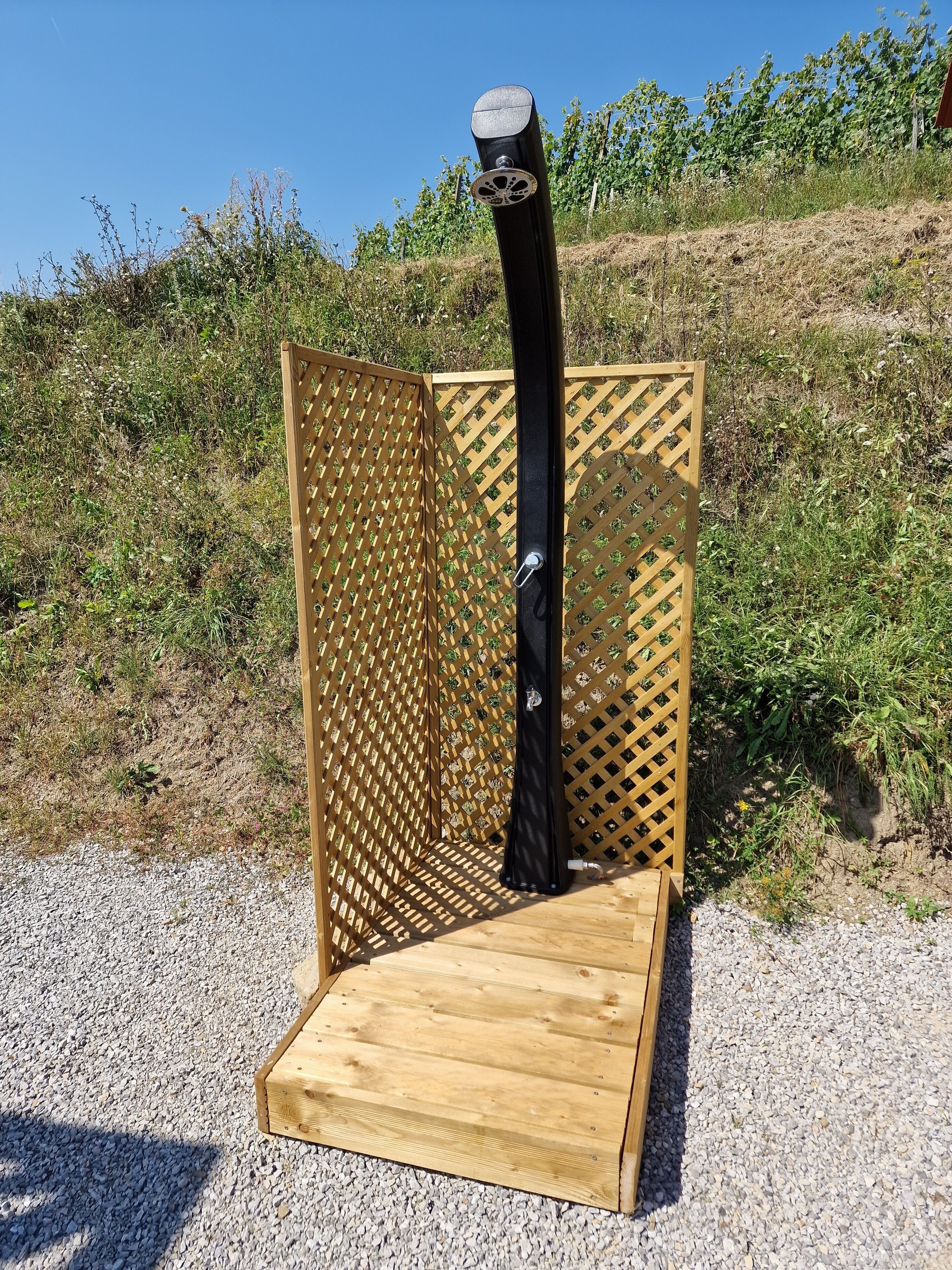 Een houten constructie met een rasterpatroon, een zwarte paal en een metalen voet.