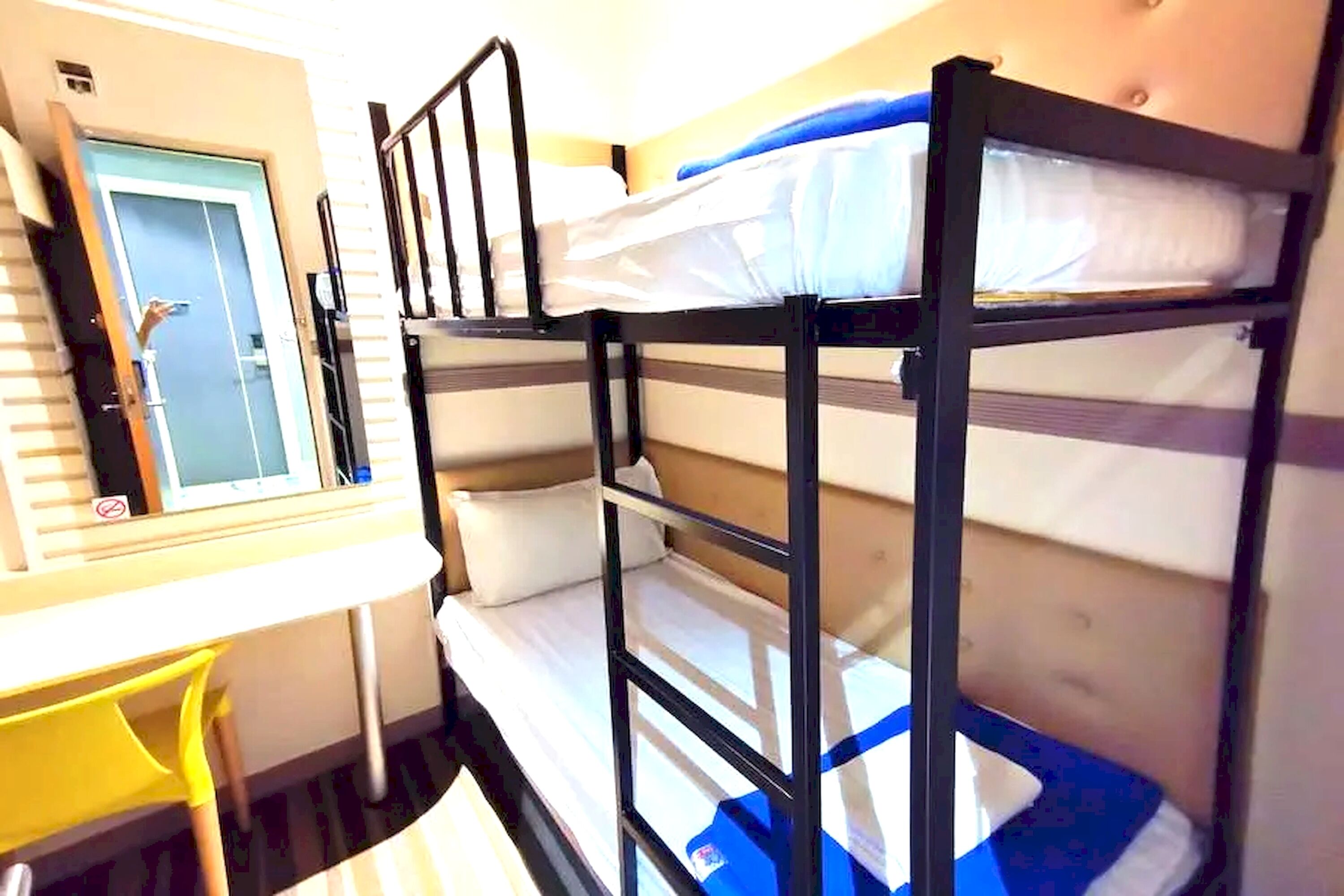 A bunk bed room with a desk and chair, a door, and a window.