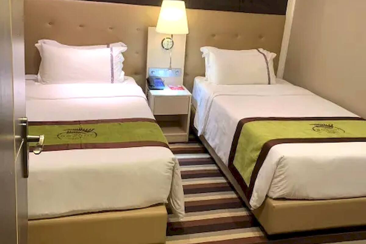 Une chambre d’hôtel avec deux lits, une table de chevet avec une lampe et un tableau accroché au mur.