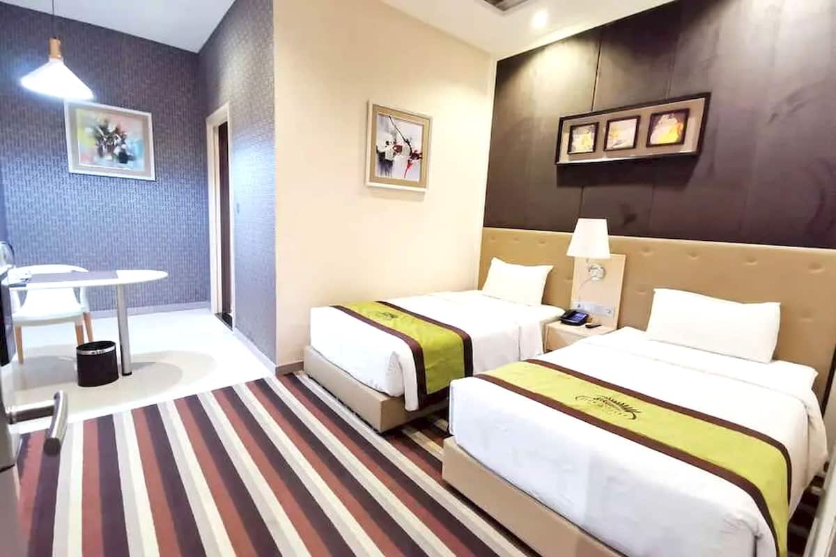 Une chambre d’hôtel avec deux lits, une petite table, une chaise et un tapis à rayures.