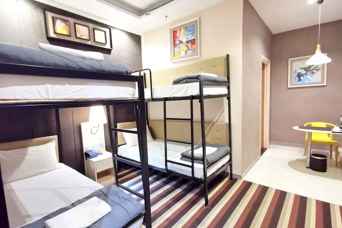 Une chambre d’hôtel avec des lits superposés, un petit bureau, une chaise et une lampe.