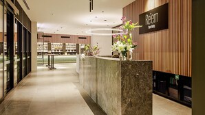 Una moderna zona de recepción de hotel con mostrador de mármol, paneles de madera y un cartel que indica "Réem Yarm Valley".