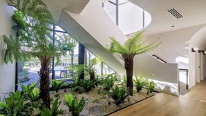 Un interior moderno con un amplio jardín interior, una escalera y ventanas grandes.