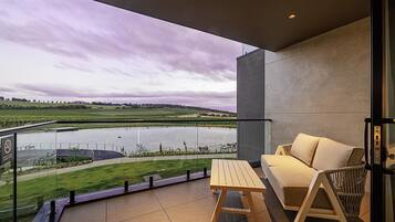 A balcony with a view of a lake, a wooden table, and a sofa.