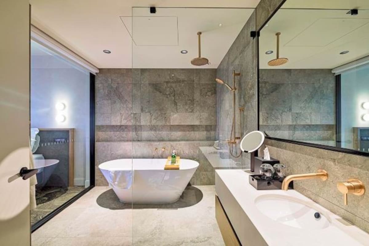Un baño moderno con una bañera independiente, un espejo grande y un tocador con lavabo.
