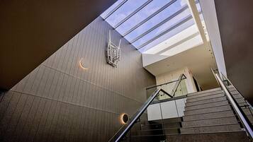 A modern interior with a glass ceiling, a staircase, and a patterned wall.