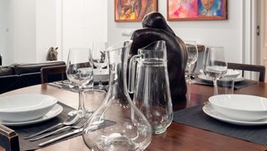 A dining table set with clear glassware, plates, and cutlery, with a black sculpture in the background. - Luxury modern apartment (Roma)