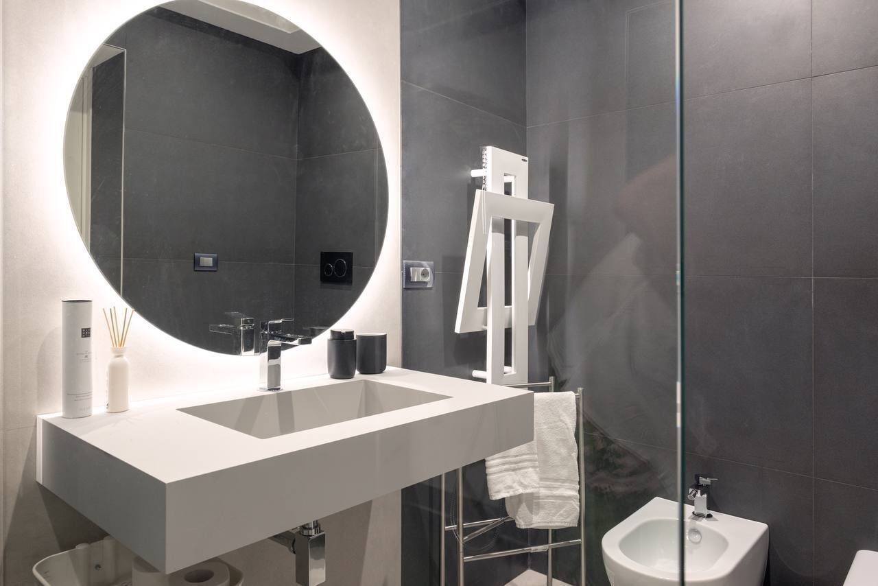Un baño moderno con un espejo grande, dos lavamanos, un bidé y un perchero para toallas.