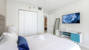 A modern hotel room with a neatly made bed, a television mounted on the wall, and a white wardrobe. - Brickell Bay View Oasis with Pool, Hot Tub, & Gym (Miami)