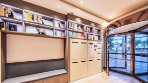 Una biblioteca moderna con estanterías, una zona de estar y vistas amplias a través de grandes ventanales.