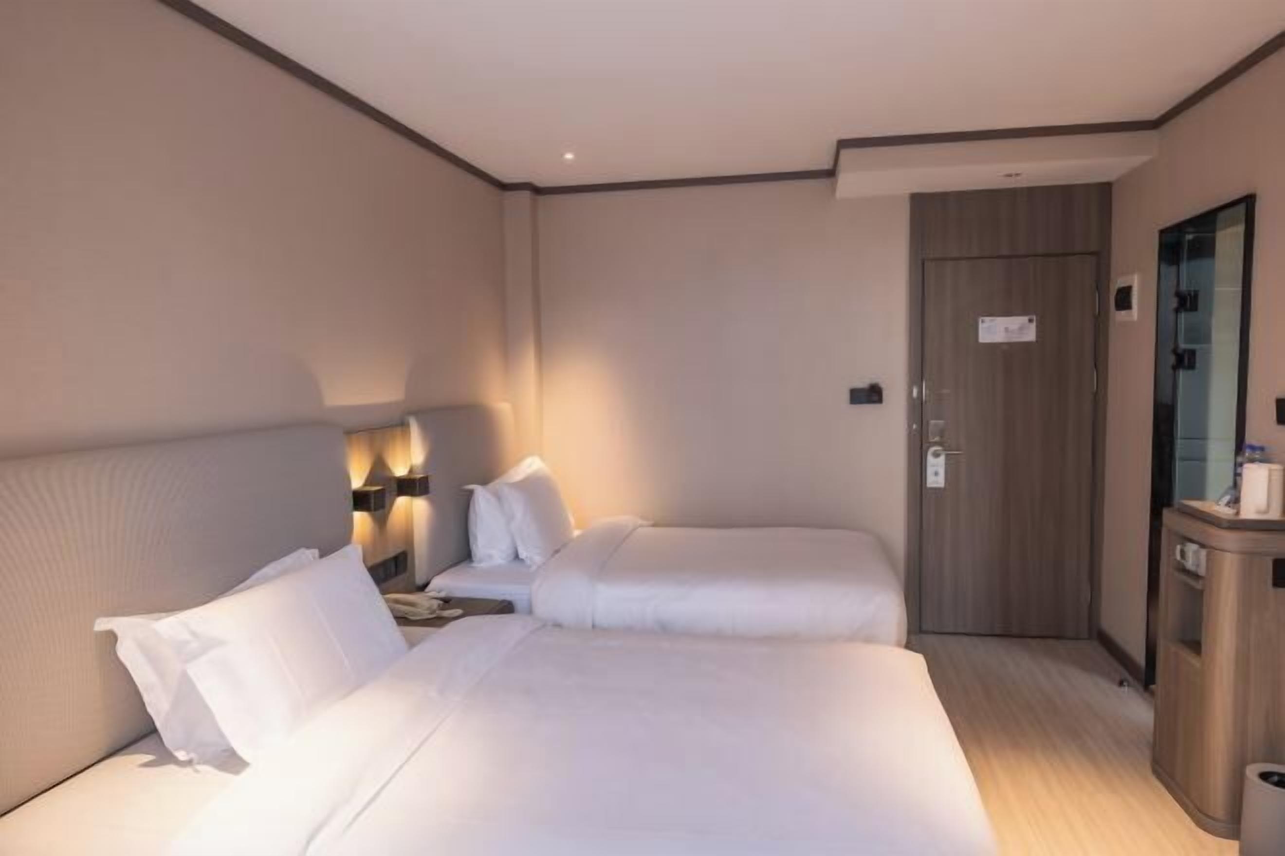 Et hotelværelse med to senge, et natbord, et skrivebord og et spejl.