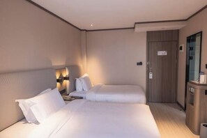 Ein Hotelzimmer mit zwei Betten, einem Nachttisch, einem Schreibtisch und einem Spiegel.