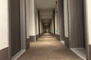 A long, narrow hotel corridor with doors on both sides and a carpeted floor. - HanTing Hotel (Tianjin Nankai Erwei Road Metro Station) (Tianjin)