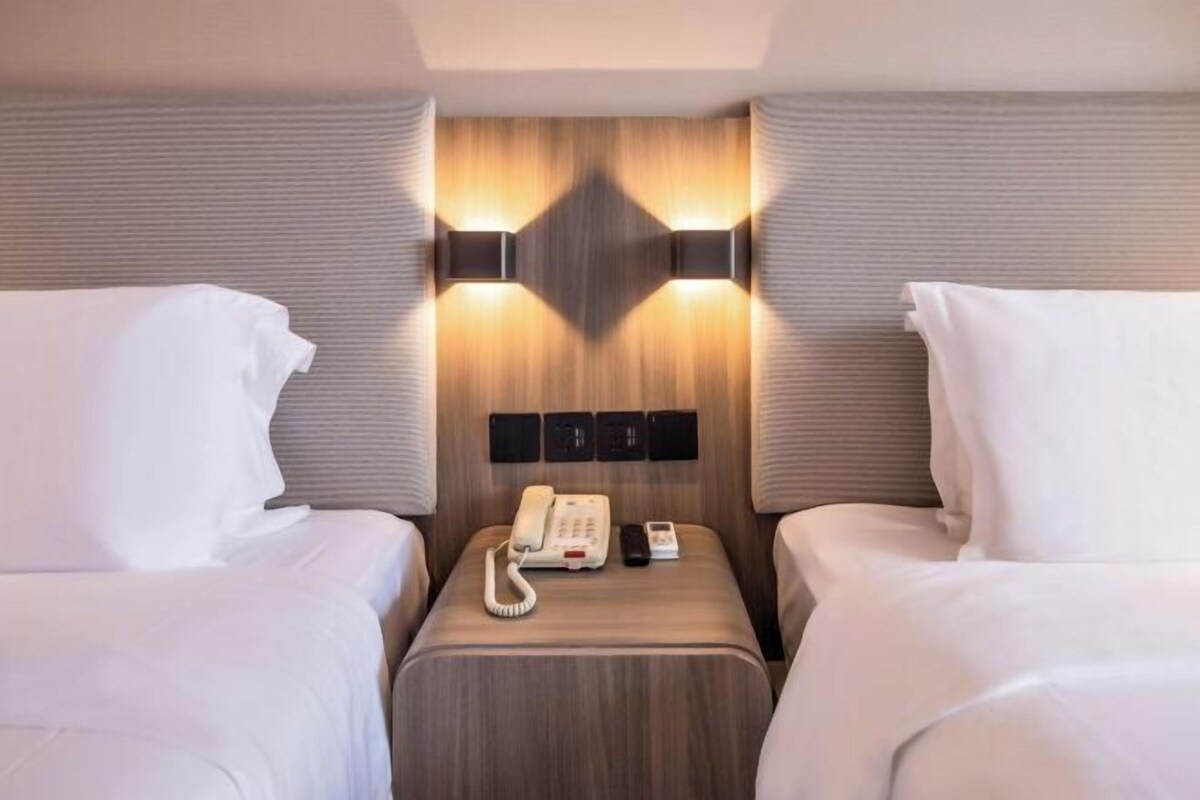 Ein Hotelzimmer mit zwei Betten, einem Nachttisch mit Telefon und Wandleuchten.