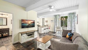 Ein modernes Wohnzimmer mit einem grauen Sofa, einem Holztisch und einem an der Wand montierten Fernseher.