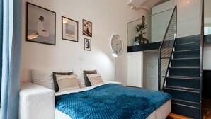 A modern bedroom with a bed, a clock, and a staircase.